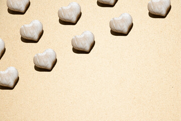 Obraz premium Neatly arranged pattern made of wooden hearts in the beach sand. Minimal flat lay. Summer love or vacation background.