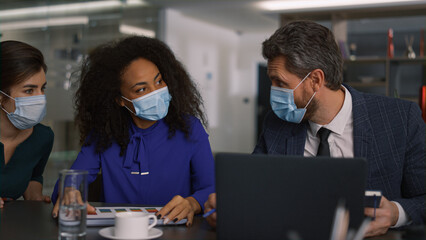 Diverse business team brainstorm together wearing protective face mask in office