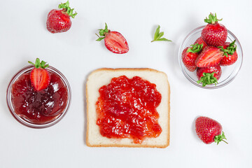Toasts with strawberry jam for breakfast on white rusric wooden background. Top view.