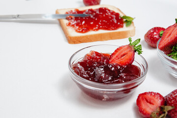 Toasts with strawberry jam for breakfast on white rusric wooden background. Top view.