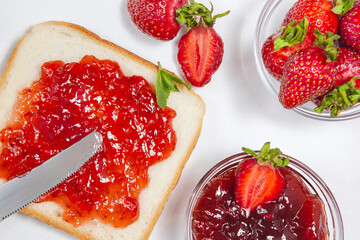 Toasts with strawberry jam for breakfast on white rusric wooden background. Top view.