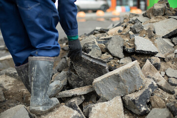 Worker carries stone. Cleaning of construction waste. Broken stone.