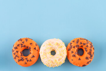 orange and yellow sprinkled  donuts on a blue background  Halloween high-quality photos for calendar and cards. Space for text