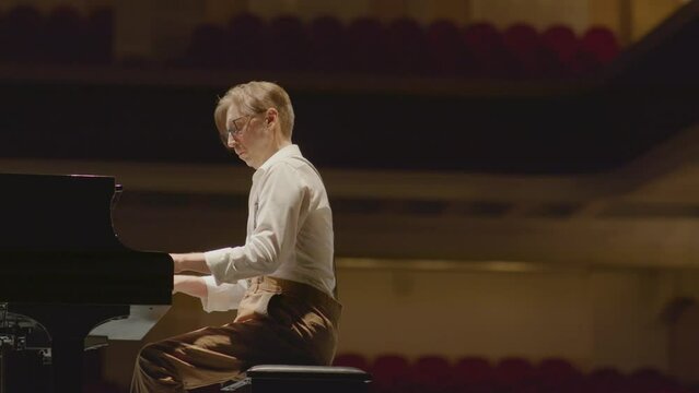 Piano player performing music on stage in concert hall while practicing before recital