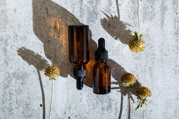 Brown serum or oil glass mock up bottle with pipette on plaster grunge background. Wabi Sabi...