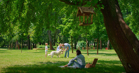 Young family have active leisure with dog outdoors. Happy picnic in green park. 