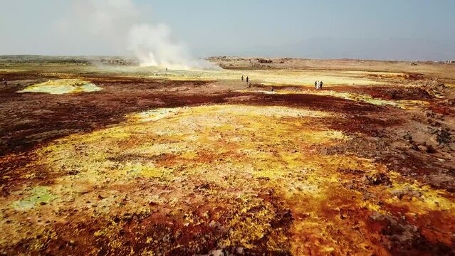 Drone flyover colorful hydrothermal field. Tourists exploring famous attraction of Dallol Volcano in Ethiopia, Africa.