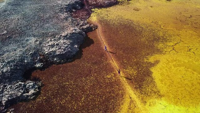 People walking on abstract colored red yellow and grey hydrothermal field at hottest place on Earth. Drone in Dallol, Ethiopia, Africa