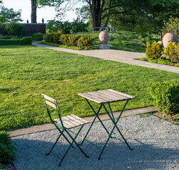 Late afternoon shadows around a wooden table and chair in Mellon Park, a city park in Pittsburgh,...