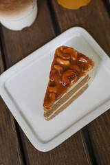 Toffee cake with with caramelly cashew crust on top served on a white plate. Homemade cake.