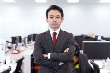 オフィスで仁王立ちするビジネスマンのポートレート