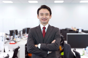 オフィスで仁王立ちするビジネスマンのポートレート