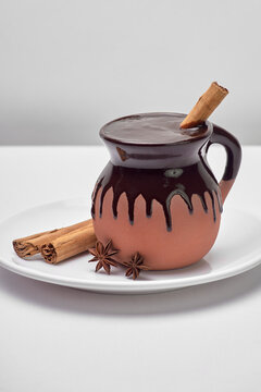 traditional mexican drink based on corn and chocolate served in a clay cup accompanied by cinnamon and anise on a white background