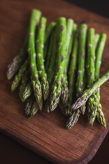 Fresh green asparagus on a wooden board top view, selective focus