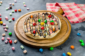 sweet pizza with marshmallows on wooden board on grey table