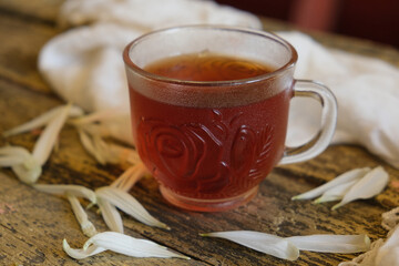 Cup of tea with white flowers petals on wooden background. Flat lay, top view