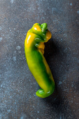 crooked bulgarian pepper, green yellow color, on blue concrete table top view
