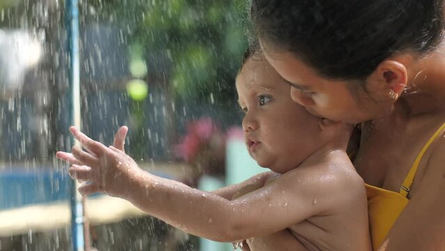 A young mother with a child, the child is up to a year old, is happy to touch the flow of water, spending free leisure time in the fresh air. Filipino mother son of a mestizo from a mixed marriage.