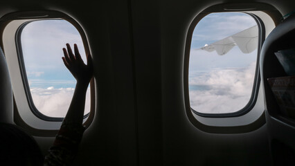 View from the window of airplane and 
silhouette of kid's hand