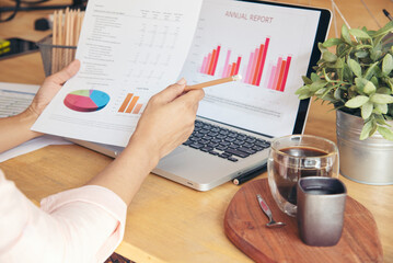 Fototapeta na wymiar Businesswoman reading financial graph charts Planning analyzing marketing data. Women hands using smartphone, laptop on office desk. Hands of young asian woman working in office firm business info.