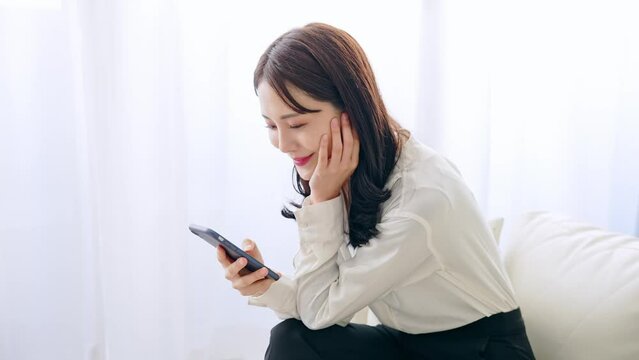 部屋でスマホを使う女性