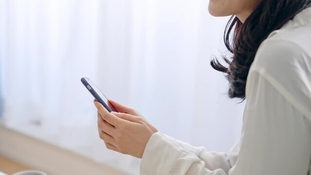 部屋でスマホを使う女性