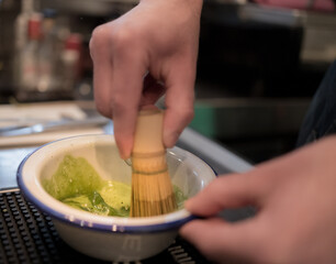 mão de um homem preparando uma bebida matcha verde.
barista preparando chá gelado.