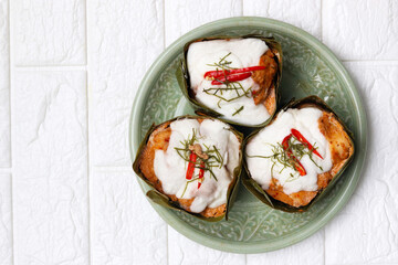 Cultural Thai food recipe, Steamed curry fish wrapped in banana leaves or Homok pla. Ingredients cooked in banana leaves include fish, vegetable, herb, chili and topping with coconut milk. 