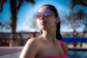 Young woman in pool with sunglasses