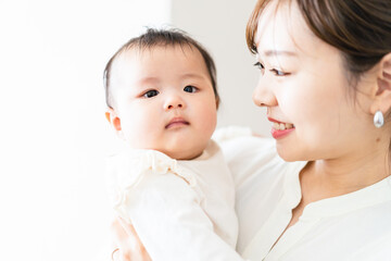 赤ちゃんを抱っこしながら家事をする若い女性