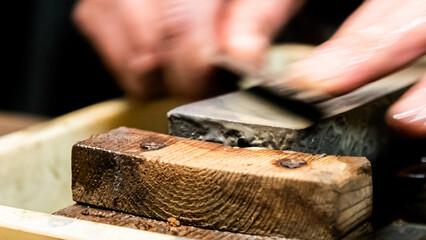 Master swordsmith is sharpening knife on grindstone with water