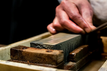 Master swordsmith is sharpening knife on grindstone with water