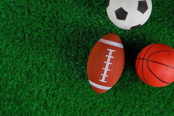 Close up of soccer, basketball and football balls on green grass background.