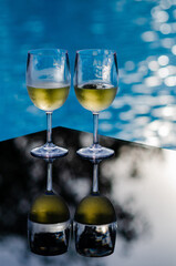 Two glasses of white wine put on table at swimming pool for Holiday and summer drink concept.