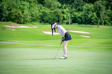 Professional woman golfer teeing  to hole  in player tournament competition at golf course for winner with green golf background.