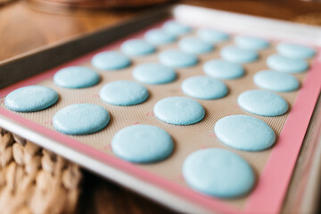 Bakery. Making macaroons. Blue macarons ready for baking lie on a tray on a wooden table. Biscuit
