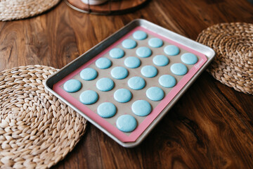 Obraz na płótnie Canvas Bakery. Making macaroons. Blue macarons ready for baking lie on a tray on a wooden table. Biscuit