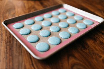 Bakery. Making macaroons. Blue macarons ready for baking lie on a tray on a wooden table. Biscuit