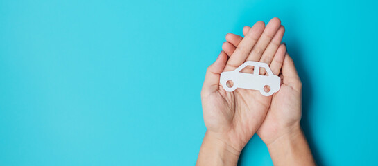 Hand holding paper Car cutout on blue background. Vehicle insurance, warranty, Automobile rental,...