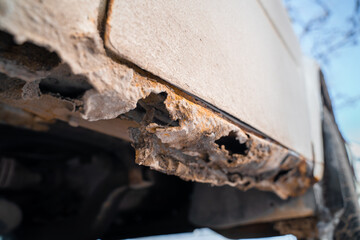 Rusted white car sills close-up. The effect of reagents in winter on an unprotected car body