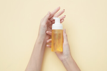 Top view of hand model holding cosmetic jar in beige background for cosmetic advertising