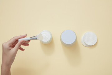 Top view of swipping cream with cotton pad in beige background 