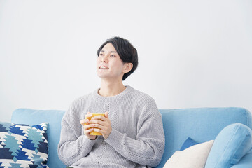 リビングでホットドリンクを飲む男性