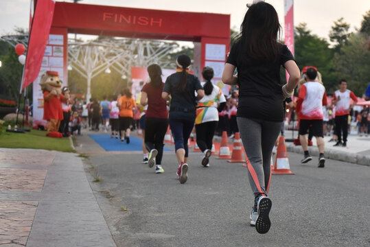 Running crowds of marathon runners, many runners past the start or finish line, women in focus.