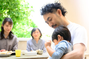 子どもをお世話する父を見守る祖母や母