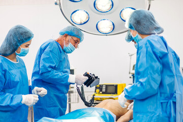 Professional anesthesiologist doctor medical team and assistant preparing patient to gynecological surgery performing operating with surgery equipment in modern hospital operation emergency room