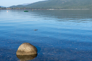 View across Lake Te Anau to Keplar Mountains with three posts land three orange buoys n shallow...