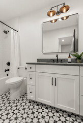 Beautiful bathroom in new luxury home. Features vanity with faucet, sink, mirror, cabinets, and sconce lights.