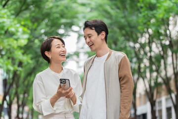 携帯を持ち笑顔で見つめ合う日本人夫婦・カップル