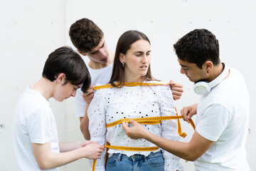 Teenager boys measuring girl with tape. Body perfection and social pressure on women concept.